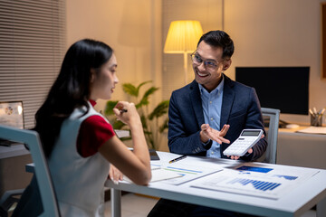 Two businesspeople discussing financial results late at the office