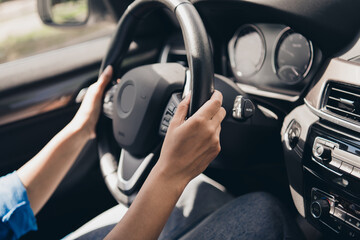 Young woman confidently driving a modern car during a sunny day, capturing the essence of urban commuting and carefree travel