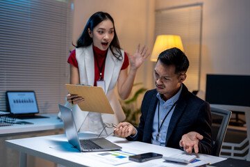 Stressed asian businessman having argument with furious boss showing business report with bad...