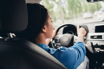 Young woman learning to drive in the city on a sunny day, practicing with confidence and focus in a...