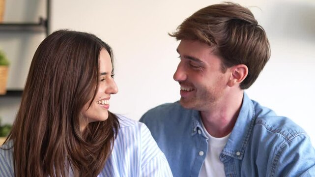 Portrait of young 20s just married couple in love posing photo shooting seated on couch in modern studio apartments, concept of capture happy moment, harmonic relationships, care and sincere feelings
