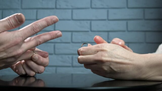 Family couple decides to separate. A view of family hands takes off their rings and put its on the table after divorce problems.