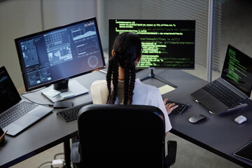 High angle shot of unrecognizable female programmer working at computer with multiple screens coding at professional workstation in office