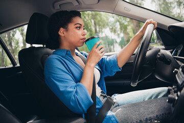 Naklejka premium Young woman enjoying a relaxing drive in the city sipping coffee with a smile
