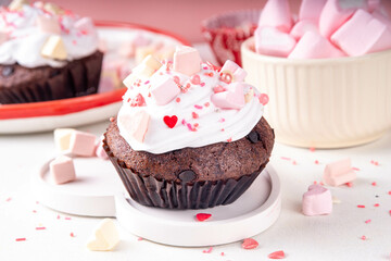 Valentine day tasty double chocolate cupcakes treat with whipped cream, heart shaped marshmallow and sugar sprinkles