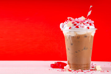 Valentine day iced coffee latte drink  with whipped cream, heart shaped marshmallow and sugar sprinkles