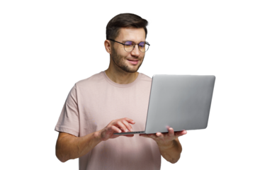 Man wearing glasses smiles while using laptop in a bright indoor setting during daylight hours