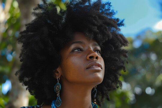 Beautiful young black woman with afro hair is looking up wearing earrings and contemplating outdoors - Powered by Adobe