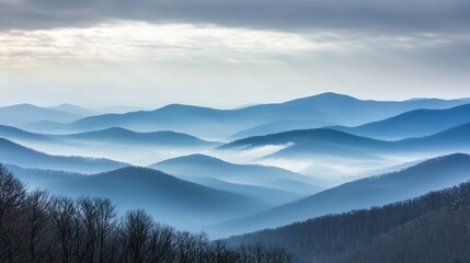 Obraz premium A mountain range shrouded in mist under a cloudy gray sky.