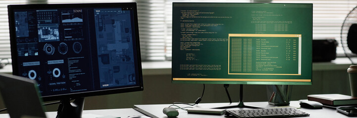 Website header shot of computers with program windows of screens standing on software developers desk at office workplace