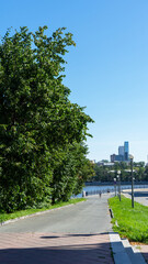 Trees on embankment of Iset River or city pond in Yekaterinburg, Russia. Vertical image