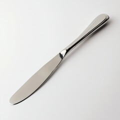 Fototapeta premium Shiny silver butter knife with a curved design resting on a plain surface