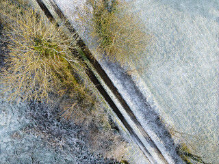 overhead view of as small single carriageway country road in winter with frost and ice