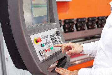 Operator using an industrial CNC machine control panel with precision and focus in a manufacturing...