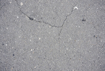 Obraz premium A close-up view of a rough concrete surface, displaying its gritty texture, small cracks, and natural imperfections with variations in shades of gray