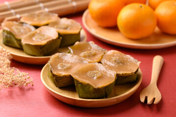 Sticky rice cake (Nian Gao), Chinese New Year cake and orange fruit on red background