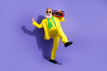 Photo of crazy cheerful eccentric elderly man wear yellow stylish costume listen music have fun isolated on purple color background