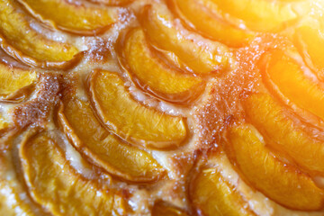 A dessert made of sliced peaches is on a wooden cutting board. The dessert is covered in sugar and looks delicious.