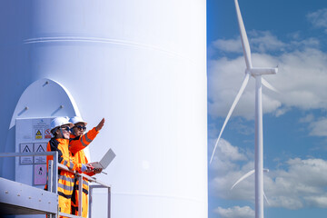 Team of male and female engineers discuss for maintenance of wind turbines at windmill field farm....