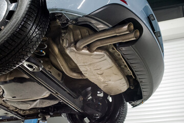 Modern car lifted on a hydraulic platform in an auto repair shop showing its undercarriage, exhaust...