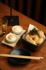 Japanese cuisine, tempura shrimp and sauce in bowl on wooden table
