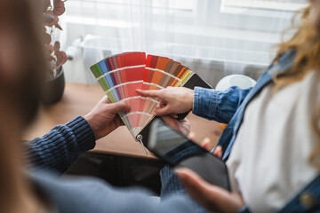 Close up on hands of unknown man and woman holding color swatches