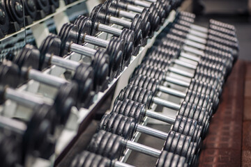 Many dumbbells are neatly arranged and waiting to be used for weight training in a russian gym