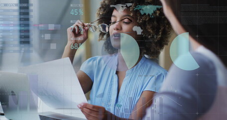 Image of data processing and diagrams over diverse female colleagues talking in office