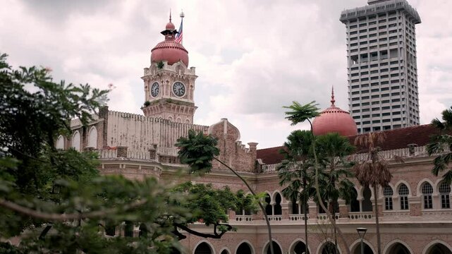 Sultan abdul samad building rising against lush greenery, showcasing iconic moorish architecture dominating kuala lumpur's historic cityscape