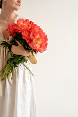 Stunning Close-Up of a Person Holding a Lush Bouquet of Bright Orange-Red Flowers, Dressed in a Light Knotted Top. Floral, Fashion, and Lifestyle Composition