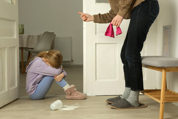 Mother yelling at daughter who spilled the glass of milk on the floor.