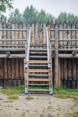 Wooden stairs leading to log reinforced defensive wall inside traditional russian fortress, highlighting medieval architectural techniques