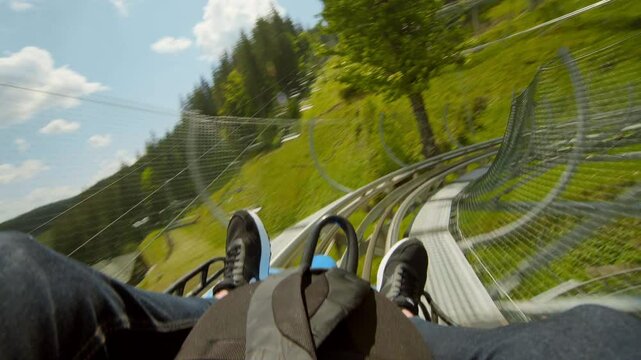 Point of view in moving action unrecognizable man coming down a mountain roller coaster on a sunny day, outdoor adventure in the mountains 4K UHD B-Roll footage