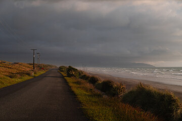 View of beautiful sunset on the shore of Cape Foulwind with beach views and rolling dark clouds (Cape Foulwind, South Island, New Zealand)