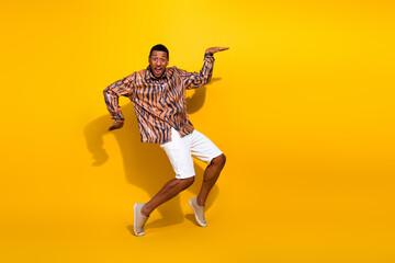 Young stylish man in tiger print shirt poses dynamically against bright yellow background, expressing fun and cheerful energy