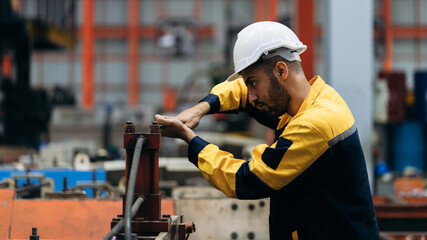 Worker inspecting factory machines, a technician working with metal sheets, and a foreman checking...