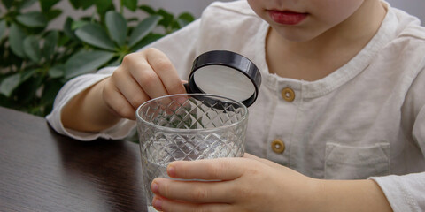 little boy looking at water through a magnifying glass, water analysis.