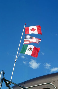 Canadian, American, Mexican flags fly from truck antenna symbolizing USMCA or NAFTA agreements.