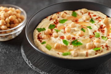 hummus with chickpeas, oil and spices in bowl, selective focus
