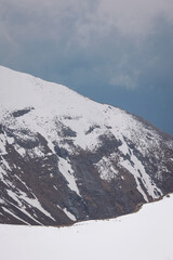 High mountains under snow. Snow-capped mountain peaks. Epic mountain landscape and dramatic sky.  Mountain peaks in winter