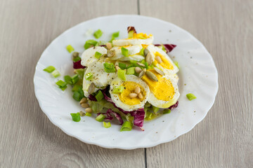 Homemade salad with greens in a plate on a wooden table
