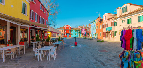 Fototapeta premium Colorful plaza with outdoor café and vibrant textiles in Burano