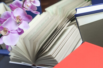 stack of books with orchid, close up. Open book on the table in library. Back to school concept....