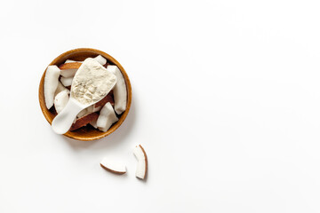 Coconut protein in spoon and bowl of coconut pieces, top view