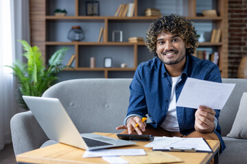 Portrait of a young man at home doing paperwork, paying credit checks, utility bills, bank bills....