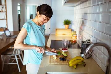 Asian woman preparing a healthy smoothie in modern kitchen