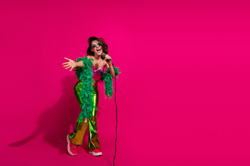 Young woman singing on a vivid pink background wearing trendy colorful outfit