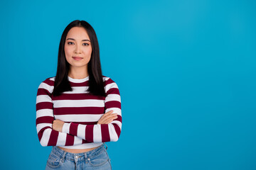 Young woman with folded arms against blue background expressing confidence
