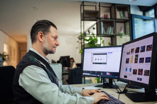 Focused businessman working on dual monitors in a modern office