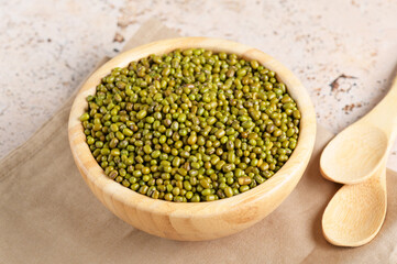 Dried mung beans in a bowl on beige table background. Healthy plant-based protein, healthy cooking ingredient for vegan recipes and vegetarian diets